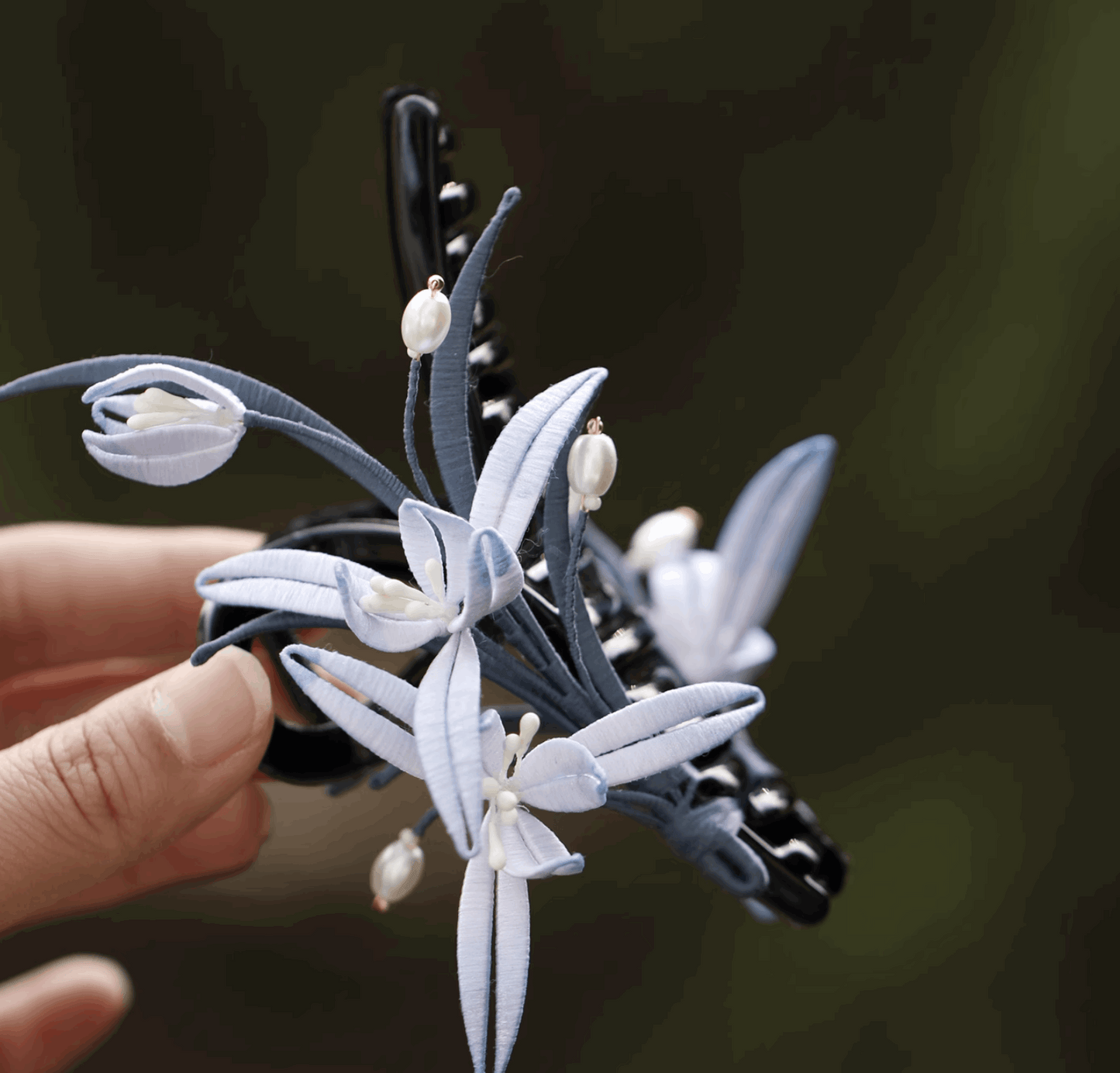 pearl with light blue flower claw clip on hair side view on hand